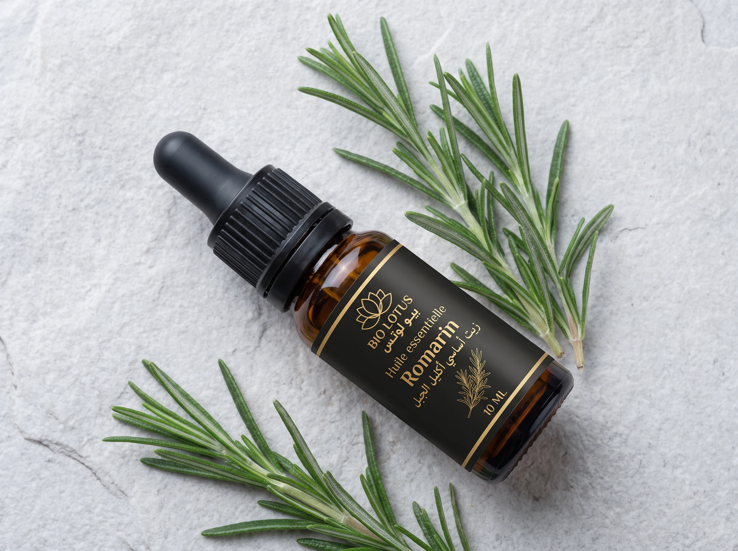 Flacon d'huile essentielle de romarin Bio Lotus posé sur marbre avec brins de romarin frais, origine botanique Rosmarinus officinalis