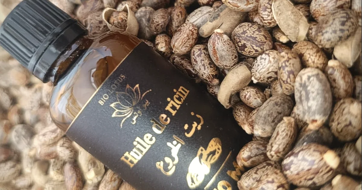 Flacons d’huile de ricin Bio Lotus posés sur des graines de ricin